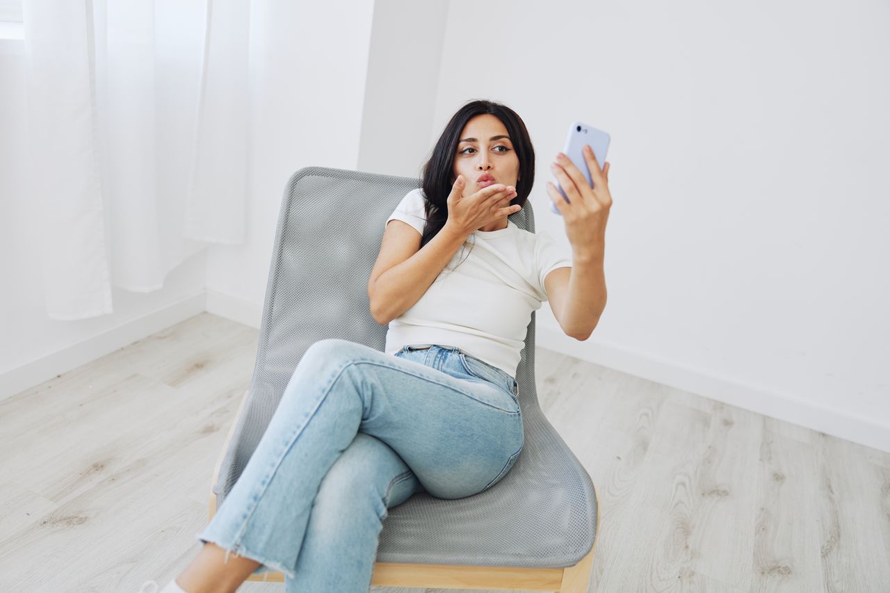 young woman using mobile phone while lying on sofa at home
