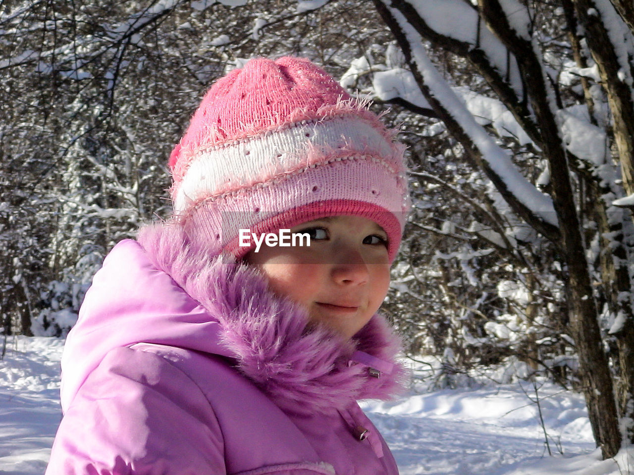 Portrait of smiling girl standing in forest during winter