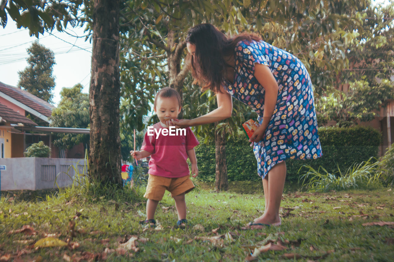 Mother feeding son playing in park