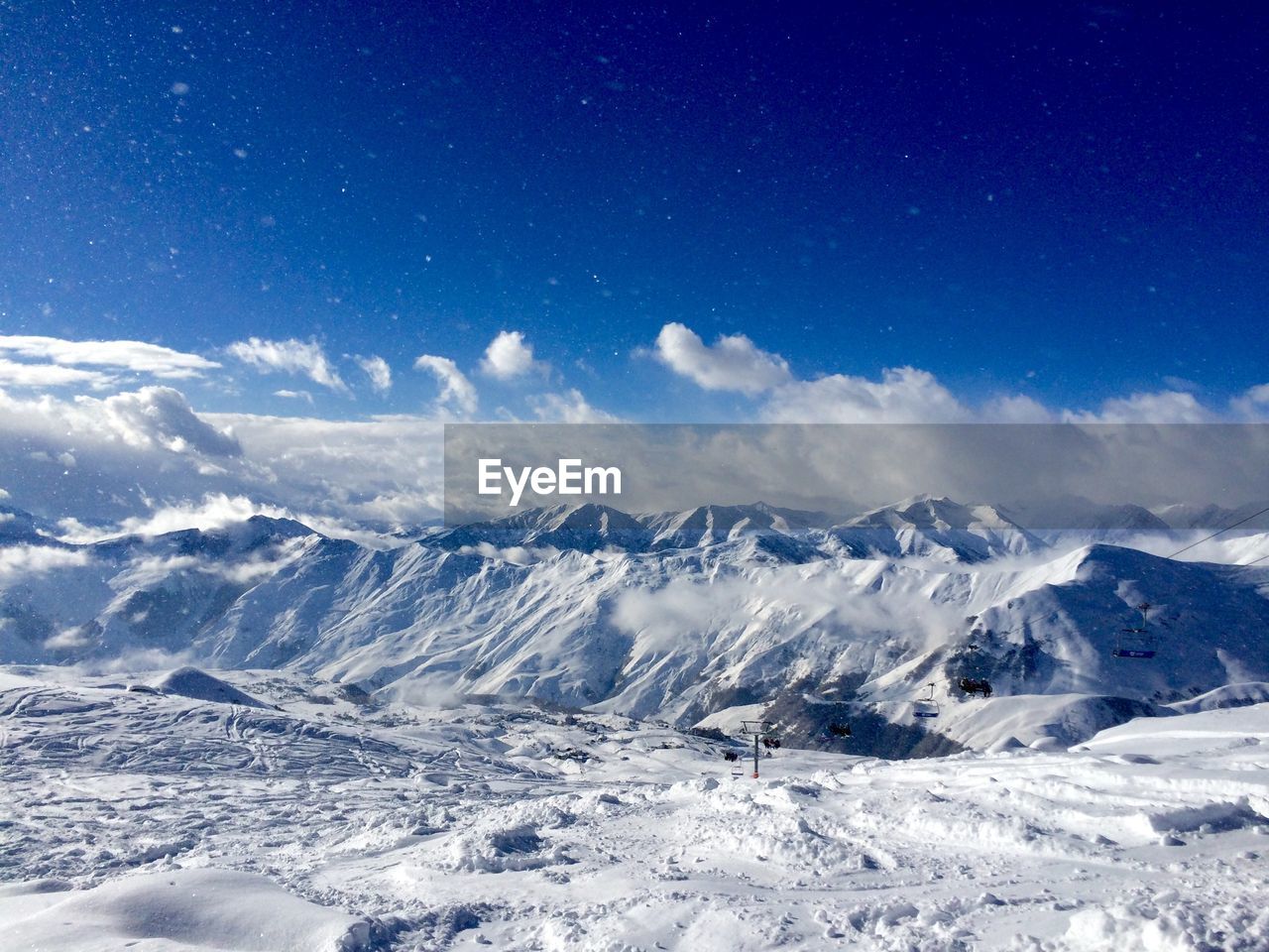 Snow covered landscape against blue sky