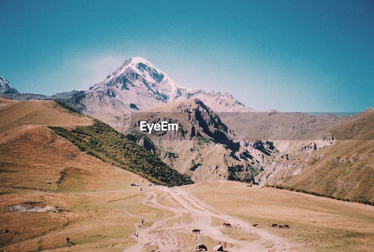 Scenic view of snowcapped mountains against clear blue sky