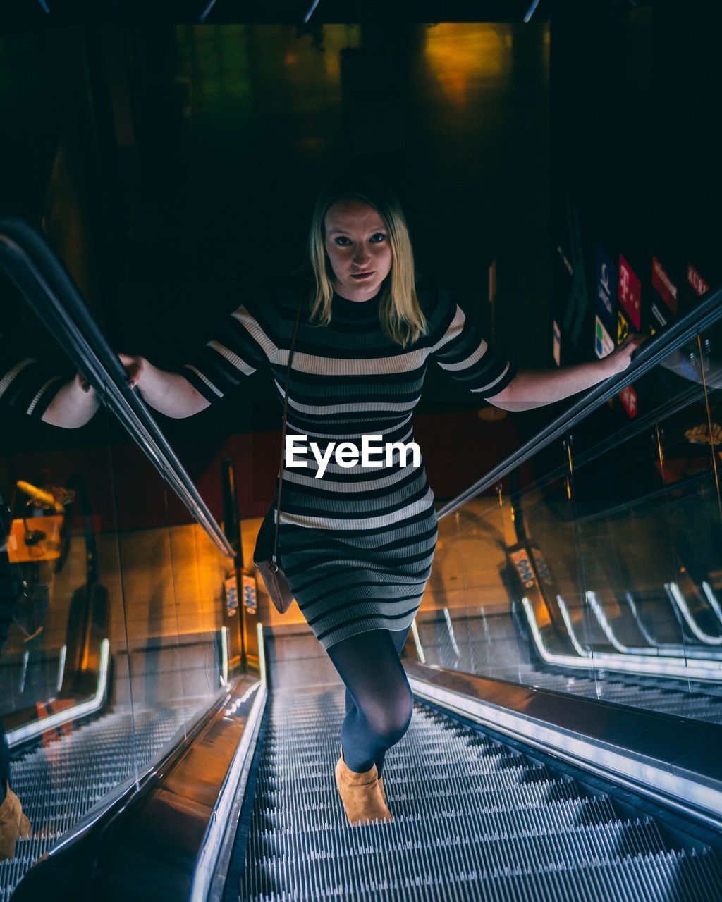 Full length portrait of young woman standing on escalator