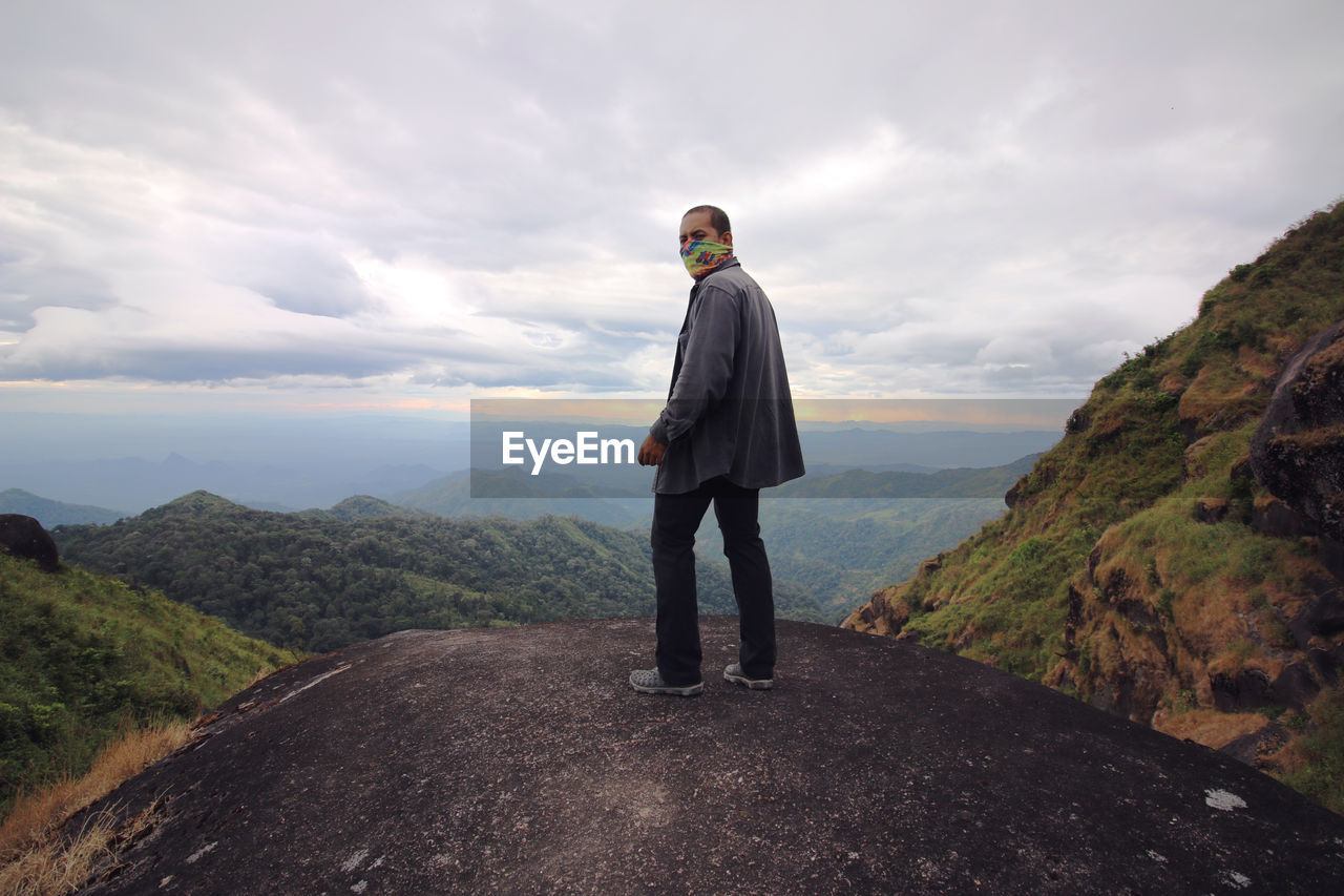 FULL LENGTH REAR VIEW OF MAN STANDING ON MOUNTAIN