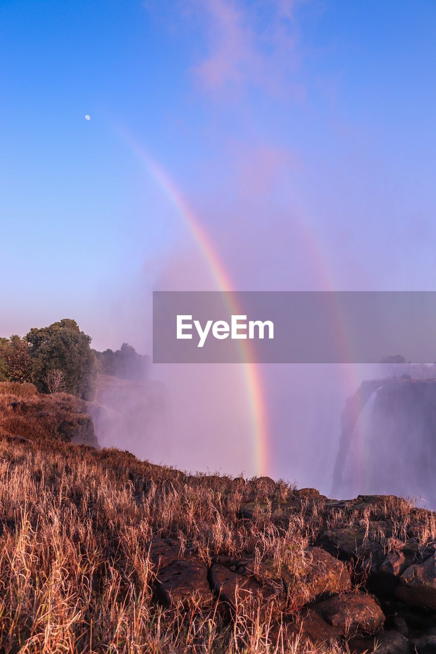 Scenic view of rainbow over landscape against sky