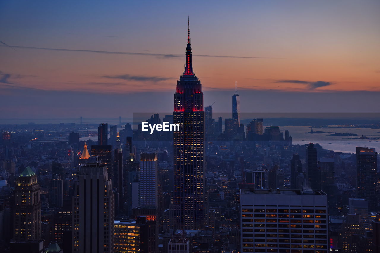 Illuminated empire state building in city against sky during sunset