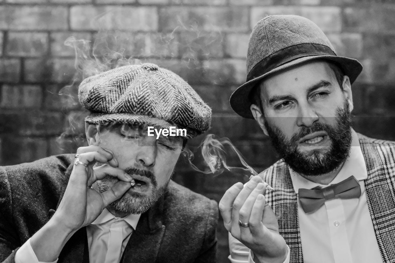 Close-up of men smoking cigarette against wall