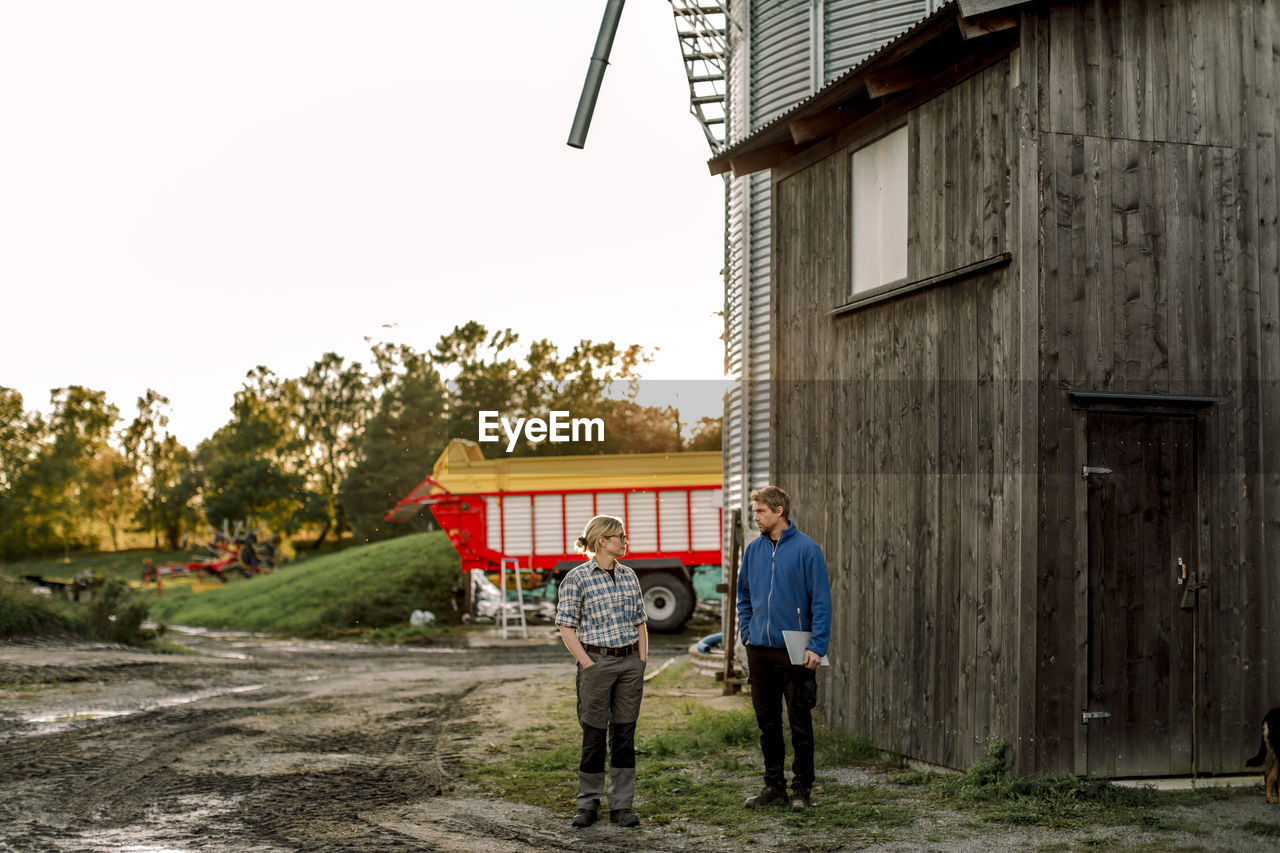 Mature farmers discussing while standing outside dairy factory