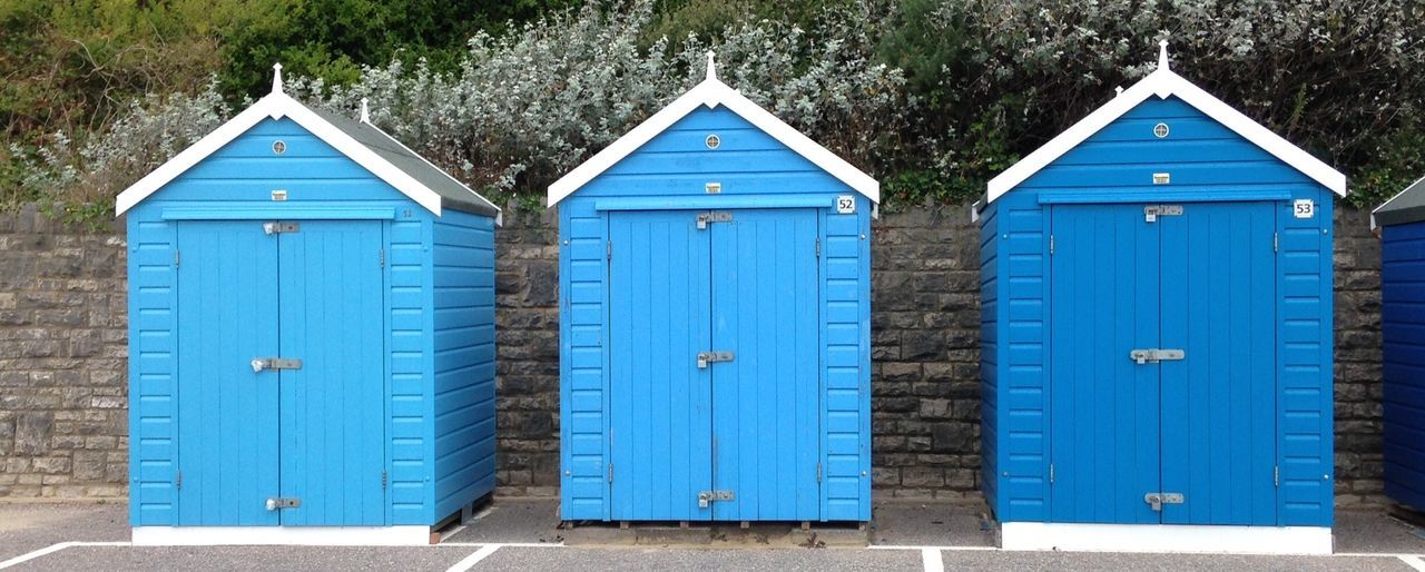 Wooden blue huts against wall