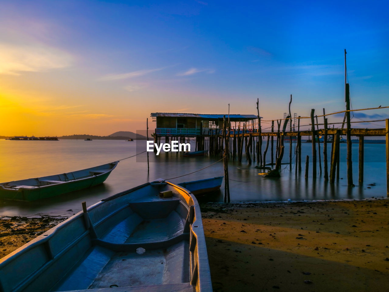 Boat moored on beach against sky during sunset