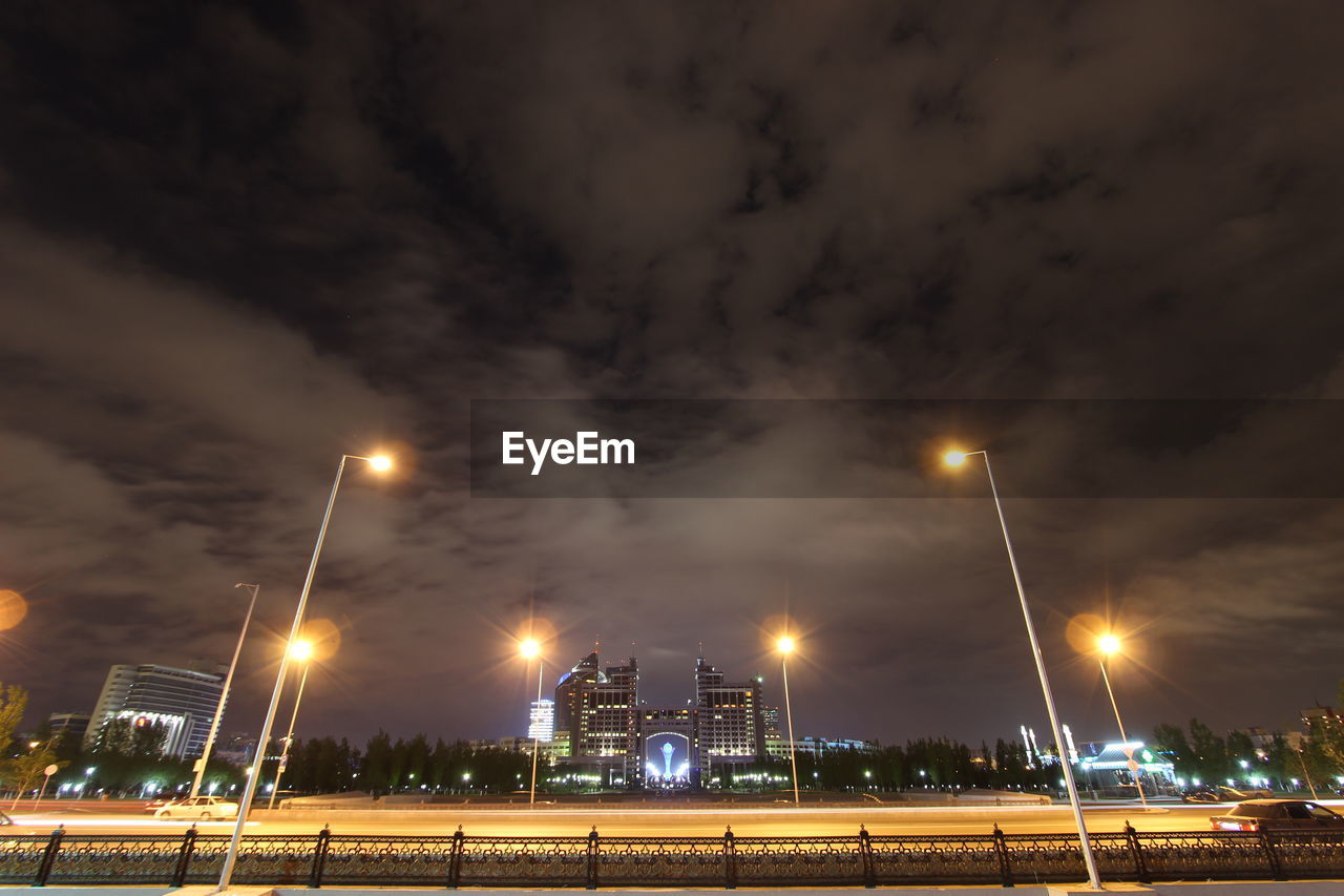 Low angle view of illuminated street light against cloudy sky