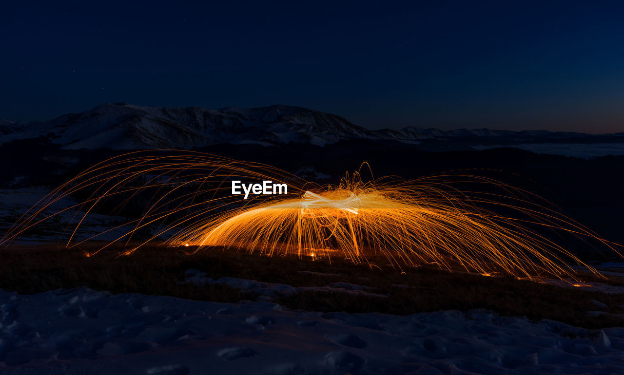 Light trails on field against sky at night