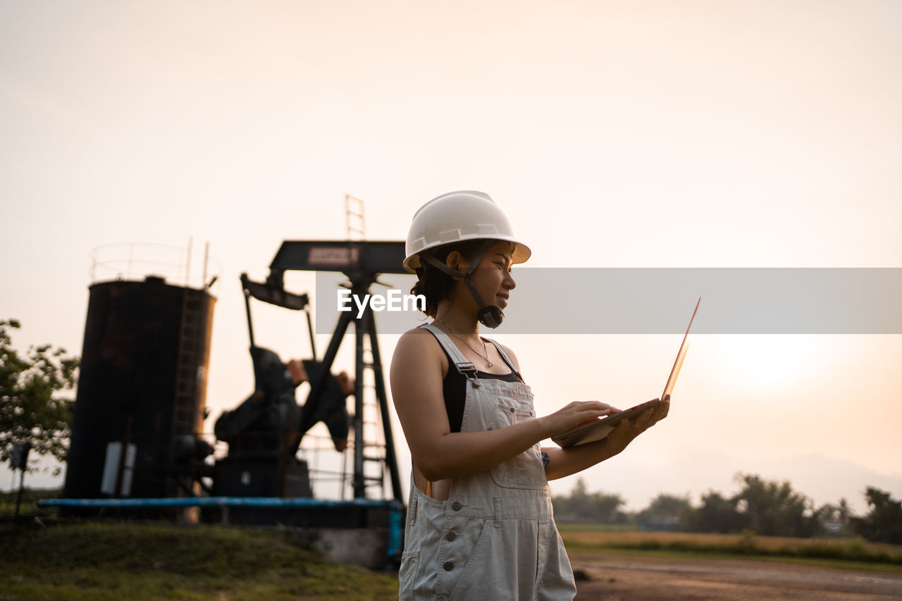  asian woman with safety helmet standing in oil refinery structure petrochemical industry.