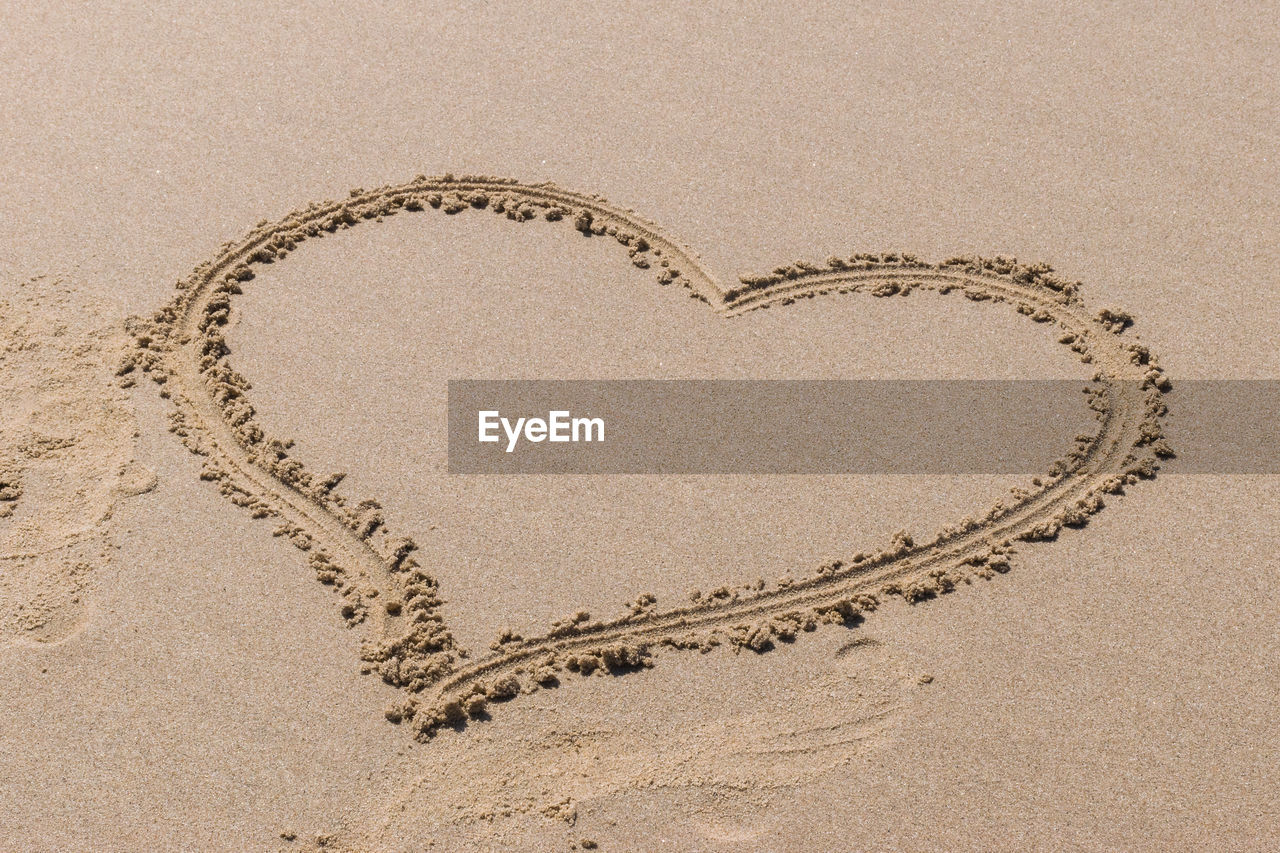 DIRECTLY ABOVE SHOT OF HEART SHAPE ON SAND AT BEACH
