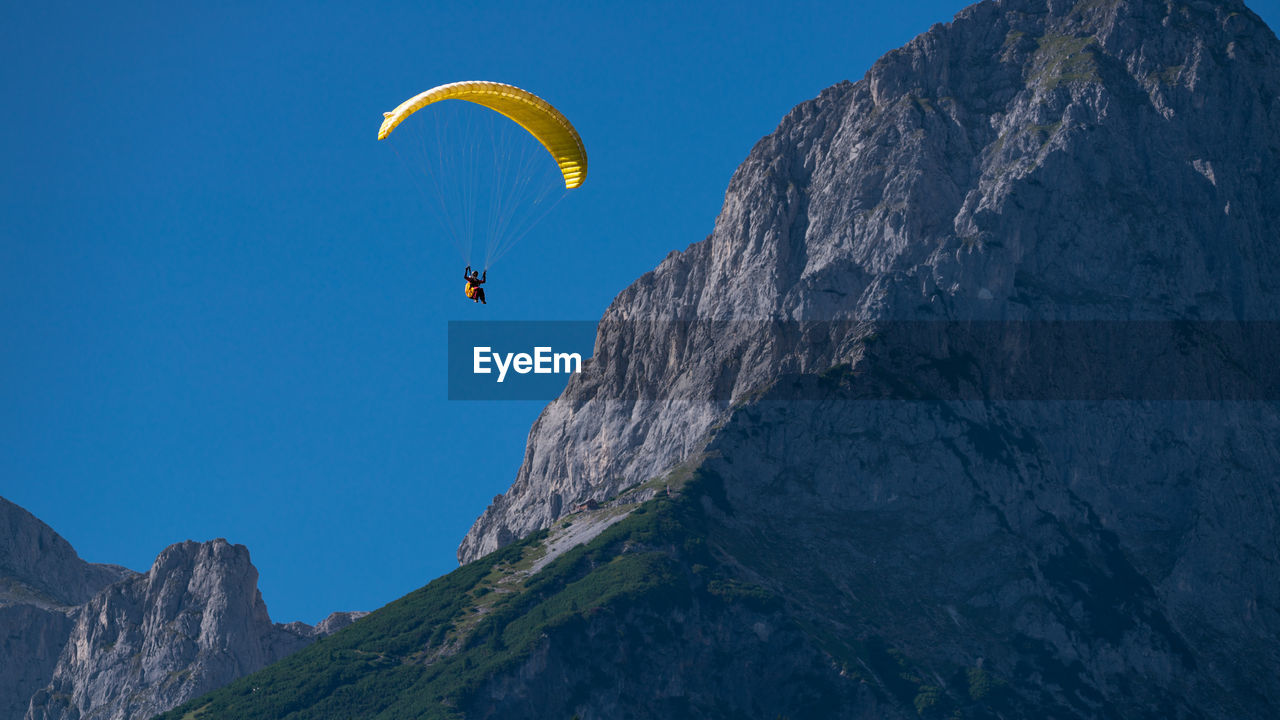 Low angle view of person paragliding against sky