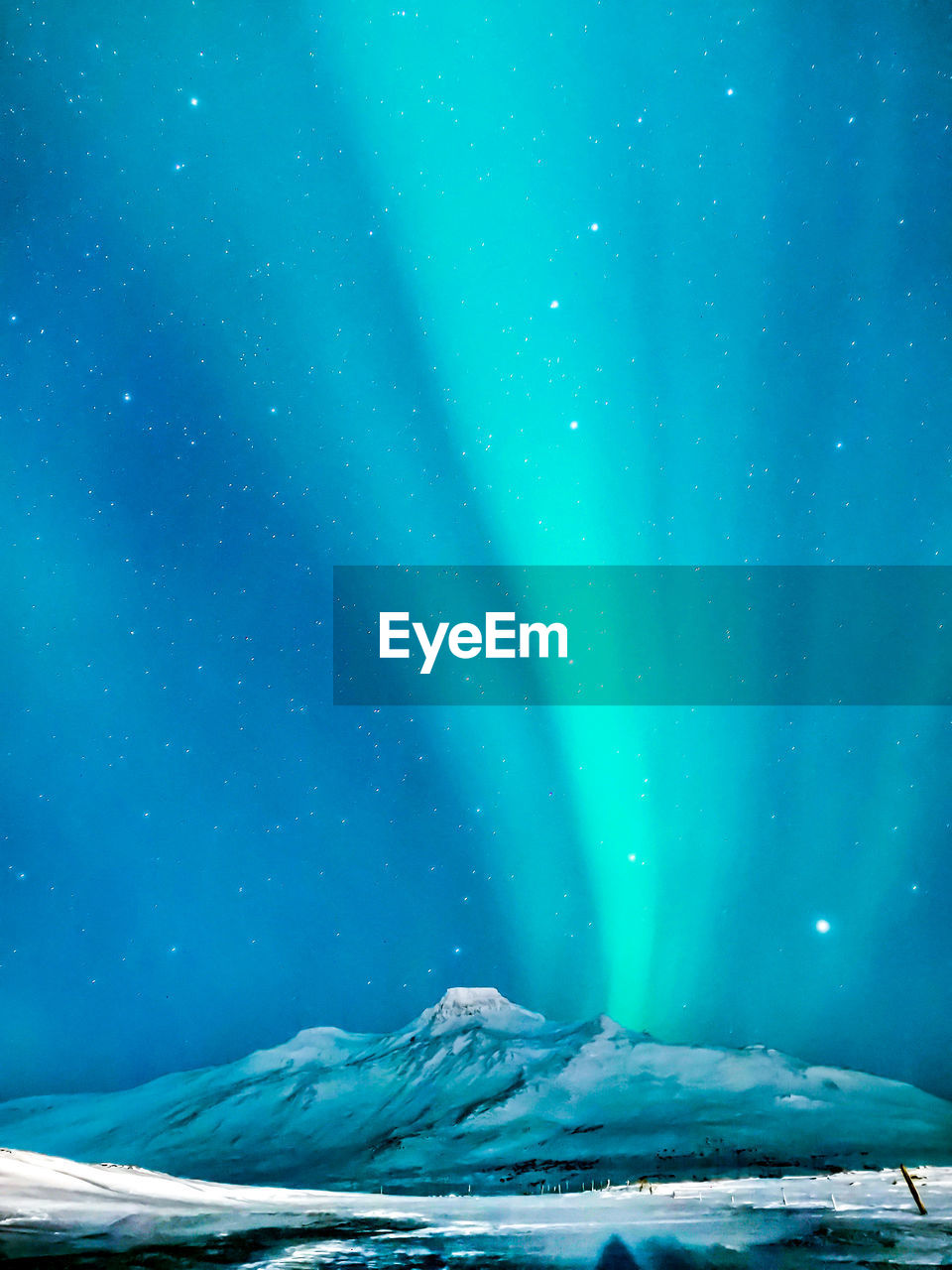 Low angle view of snowcapped mountain with aurora against blue sky at night