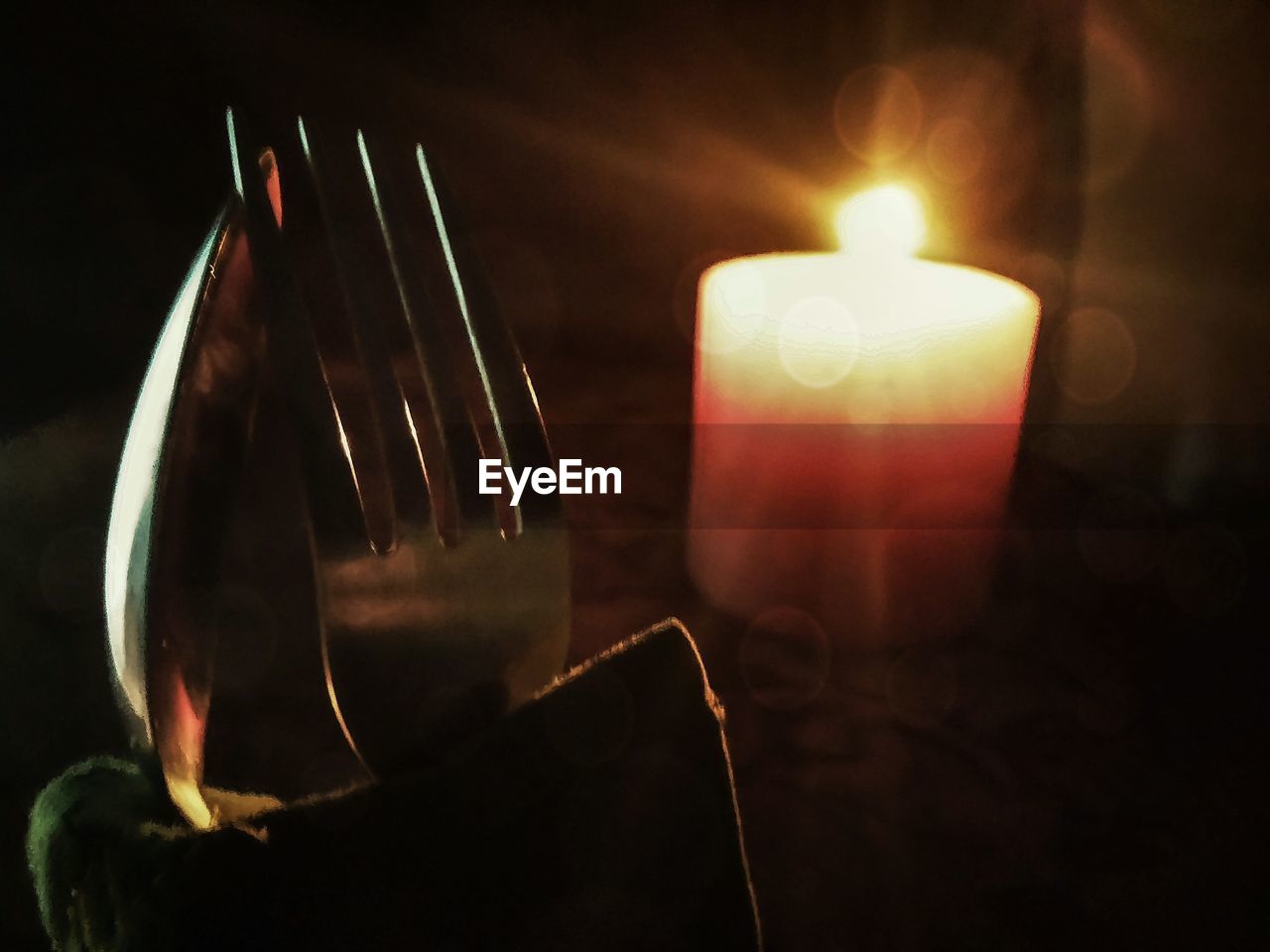 CLOSE-UP OF LIT CANDLES IN DARK ROOM