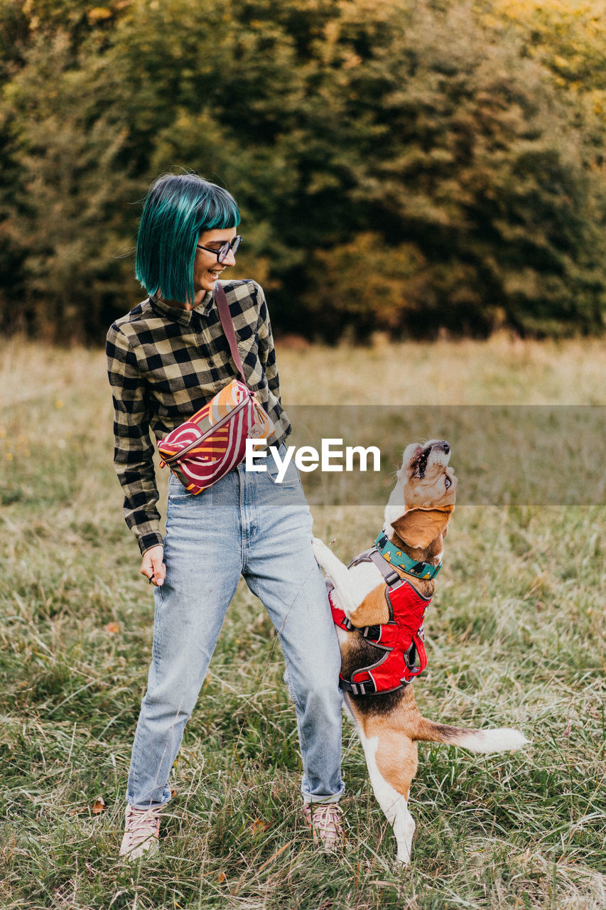 Rear view of woman with dog standing on field