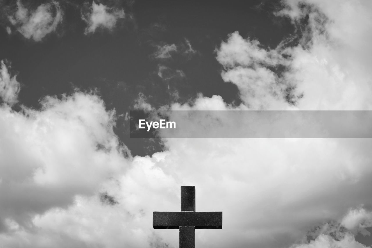Low angle view of cross against cloudy sky