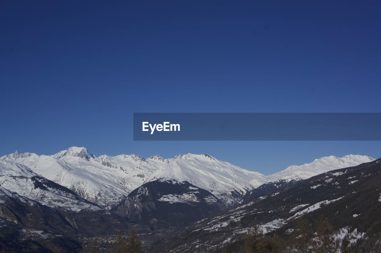 Scenic view of snowcapped mountains against clear blue sky