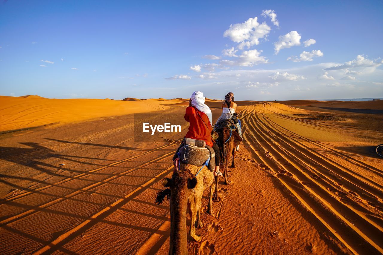 REAR VIEW OF MAN AND WOMAN WALKING ON ROAD