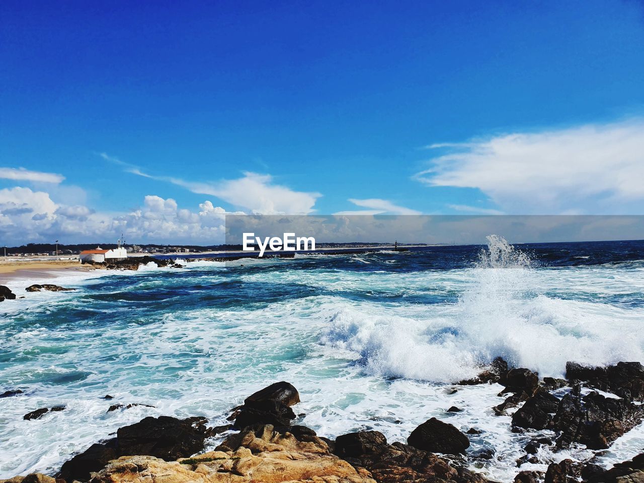 WAVES SPLASHING ON ROCKS AGAINST SKY