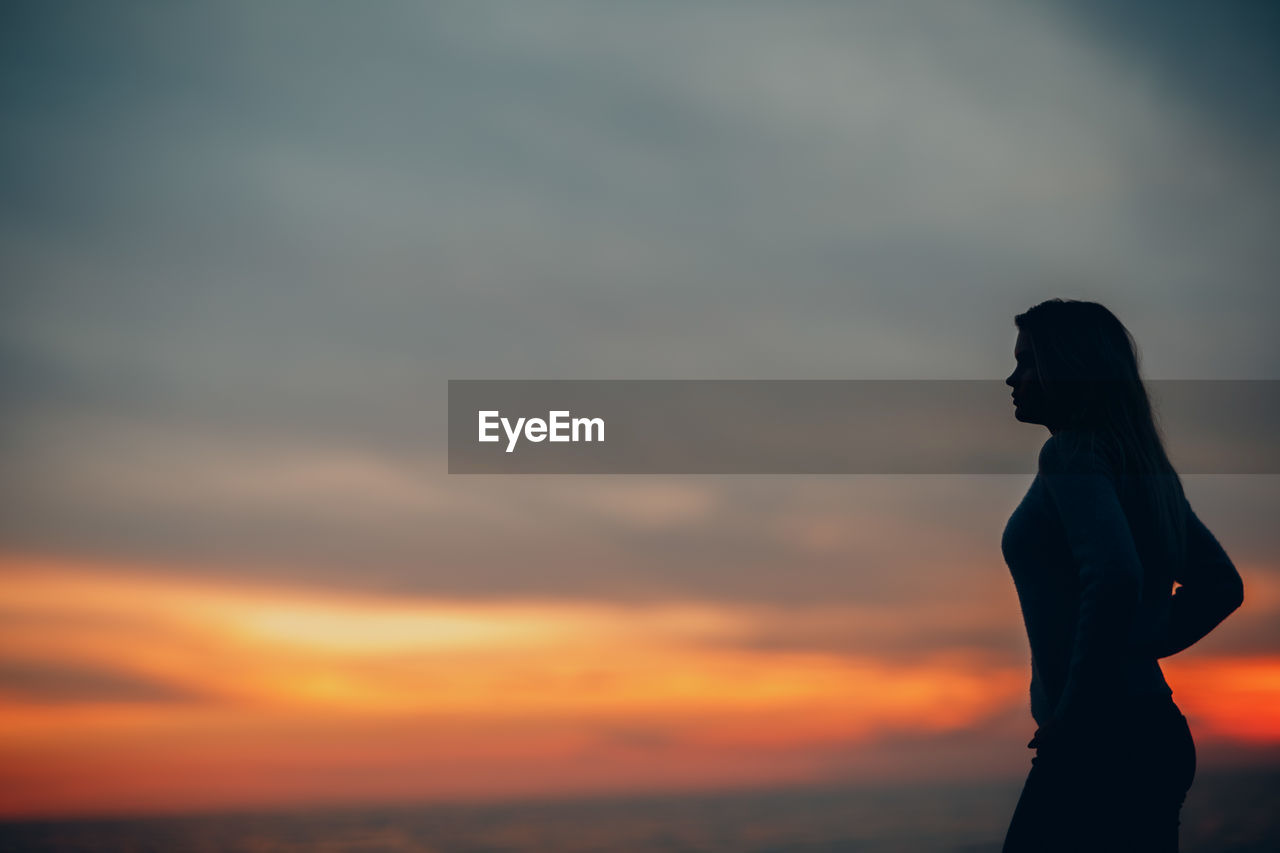 Silhouette woman standing against sky during sunset