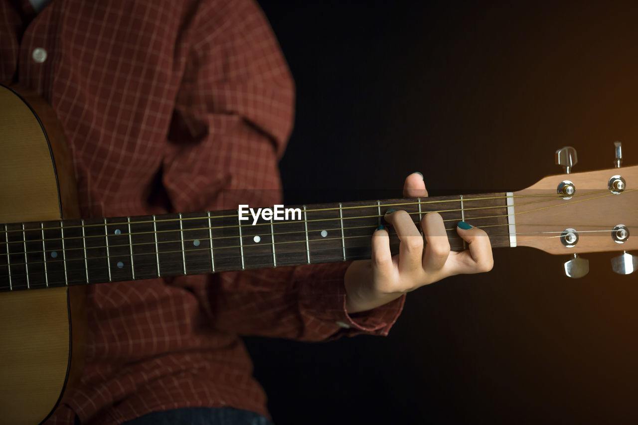 Midsection of woman playing guitar