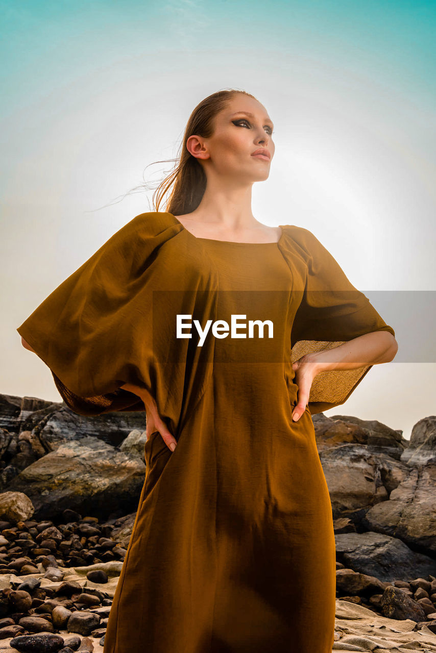 Portrait of young woman standing against sky