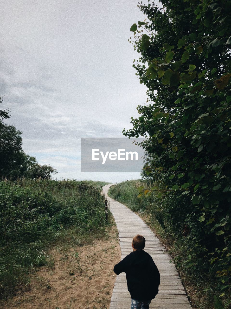 Rear view of man on footpath against sky