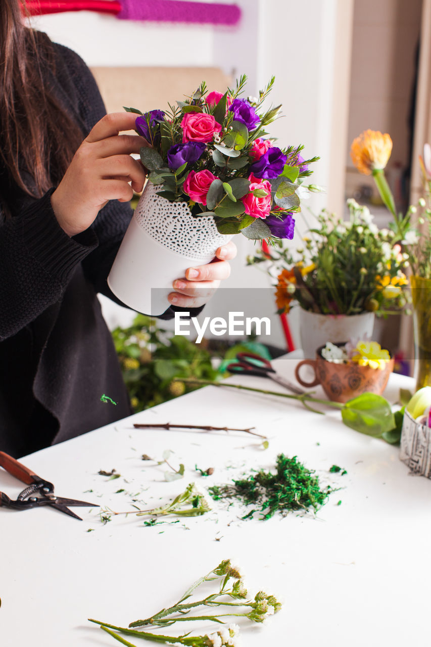 Woman holding flower vase on table