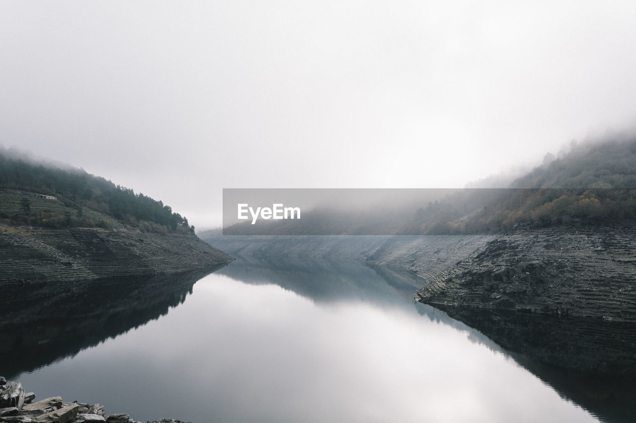 Scenic view of lake by mountains against sky