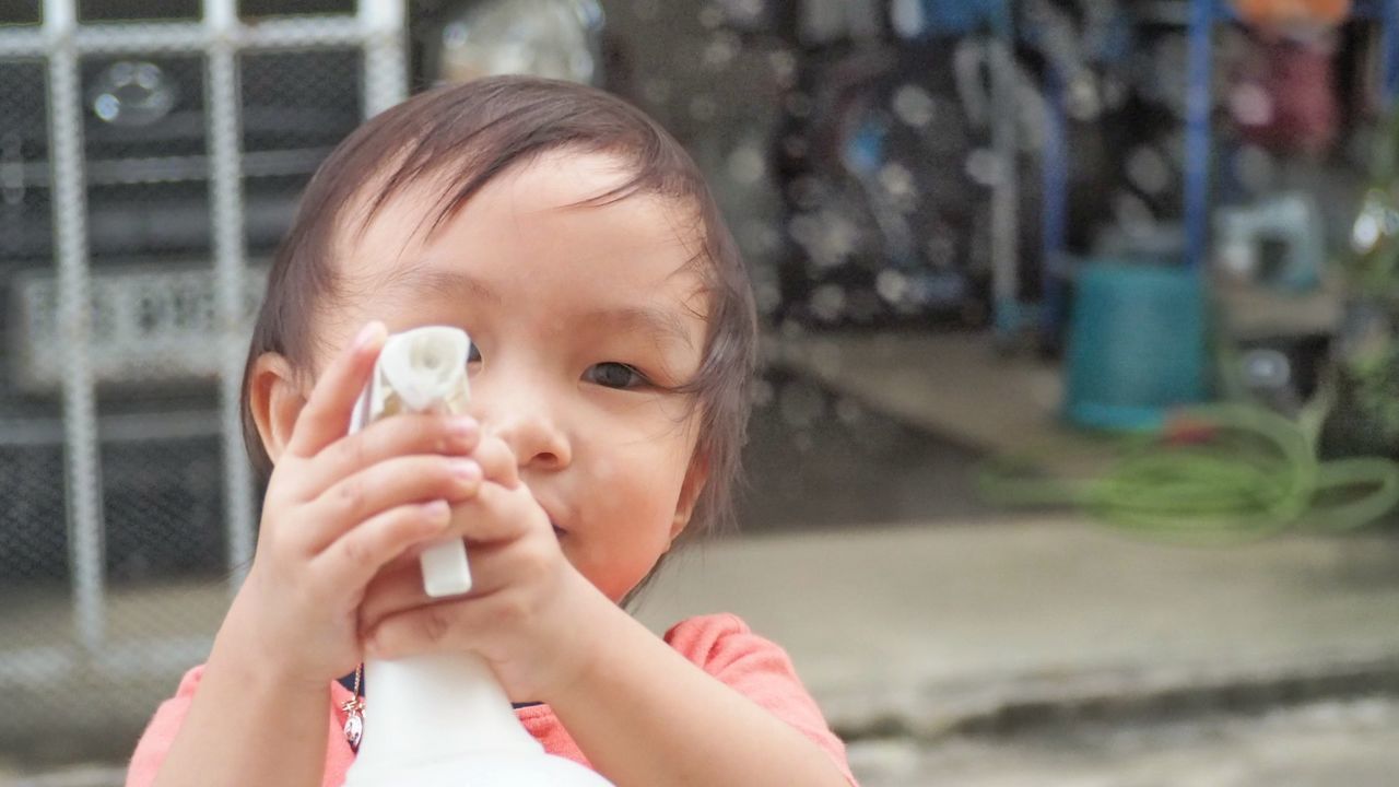 Close-up portrait of boy holding spray bottle