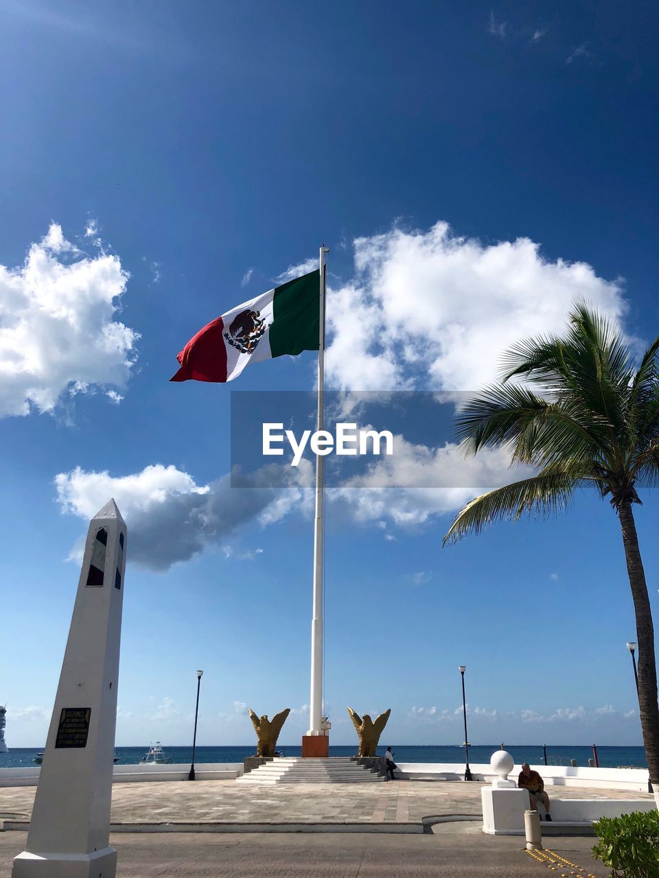 Low angle view of mexican flag against cloudy sky