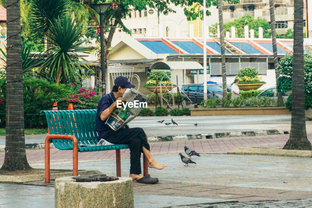 MAN SITTING ON BENCH IN CITY