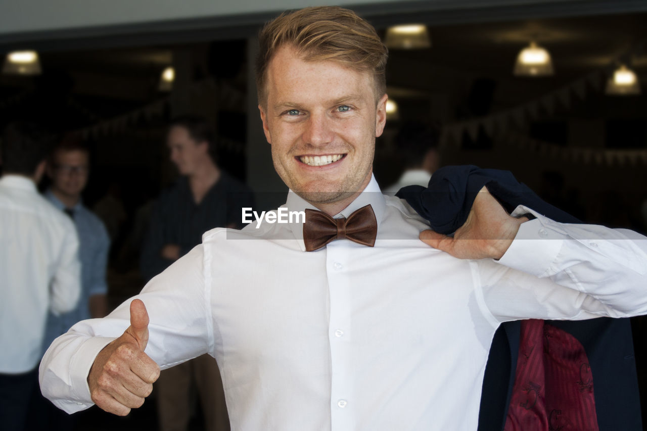 PORTRAIT OF SMILING MAN STANDING AT NIGHTCLUB