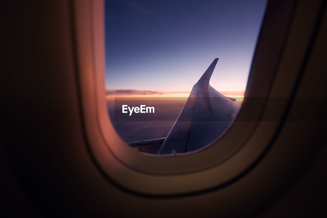 Beautiful view out of airplane window during flight at colorful sunset.