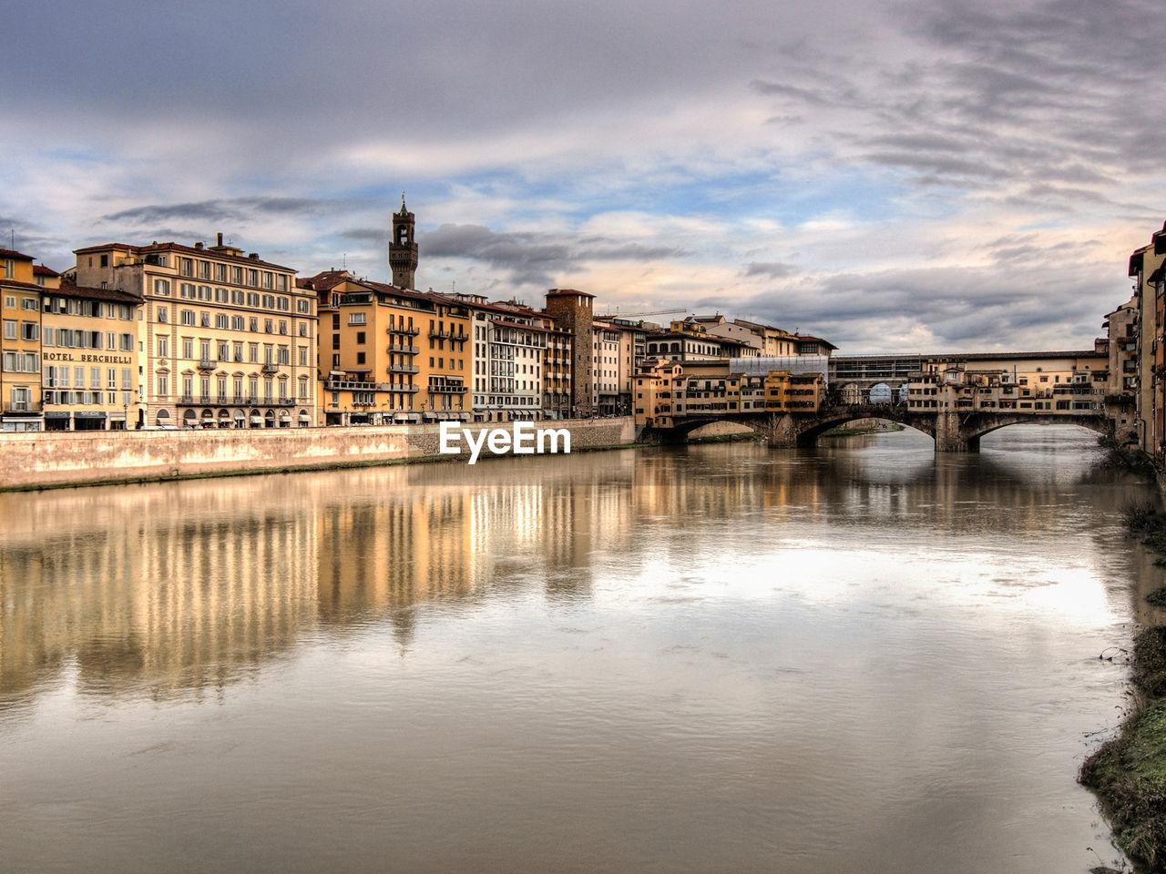 Ponte vecchio over arno river against cloudy sky