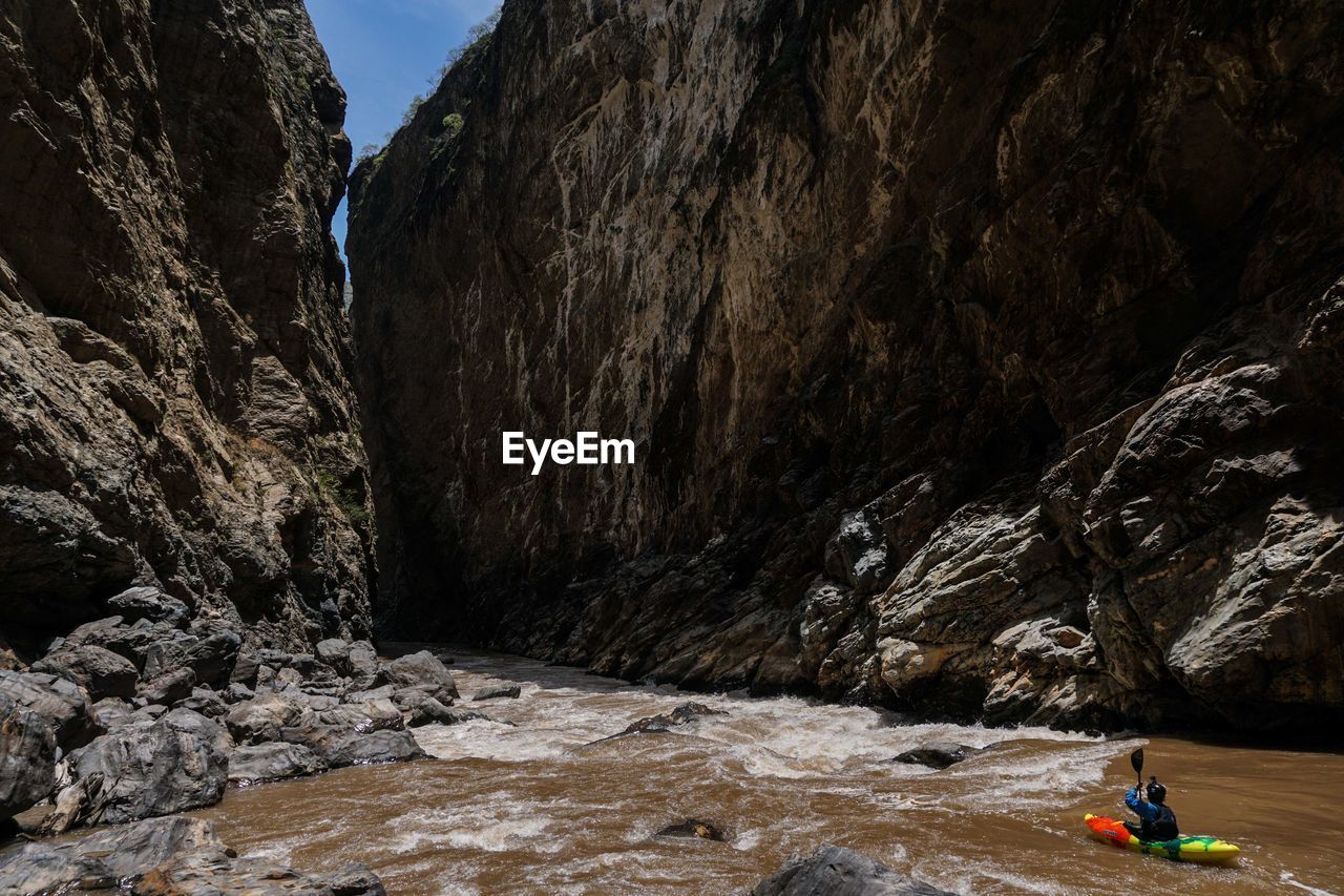 High angle view of man kayaking on river against rock formations