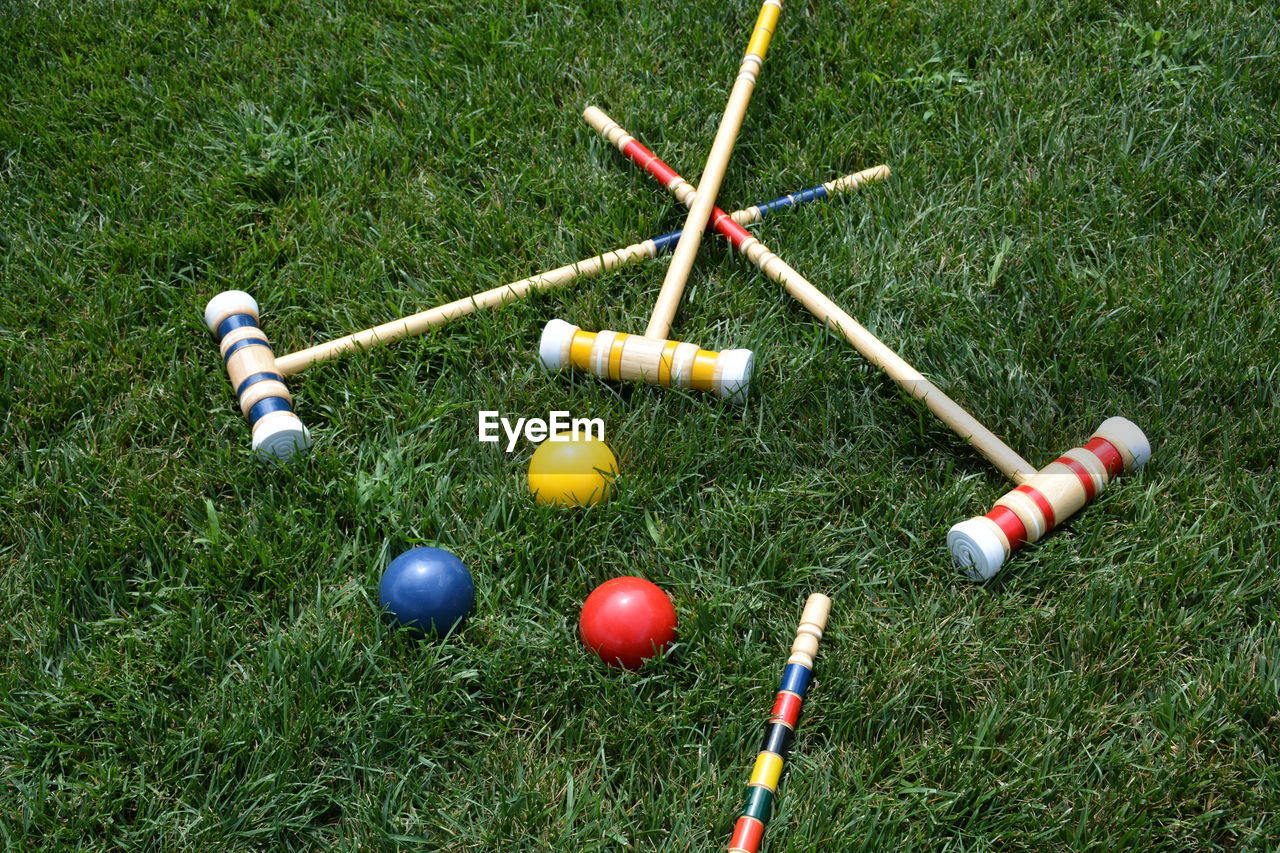 High angle view of multi colored croquet balls and mallets on grass lawn