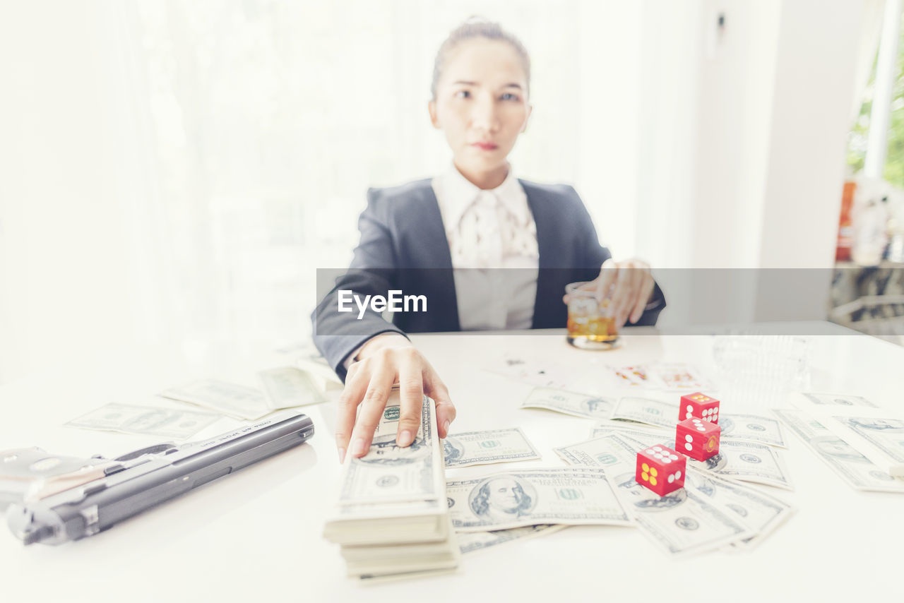 Portrait of businesswoman gambling while sitting on table at office