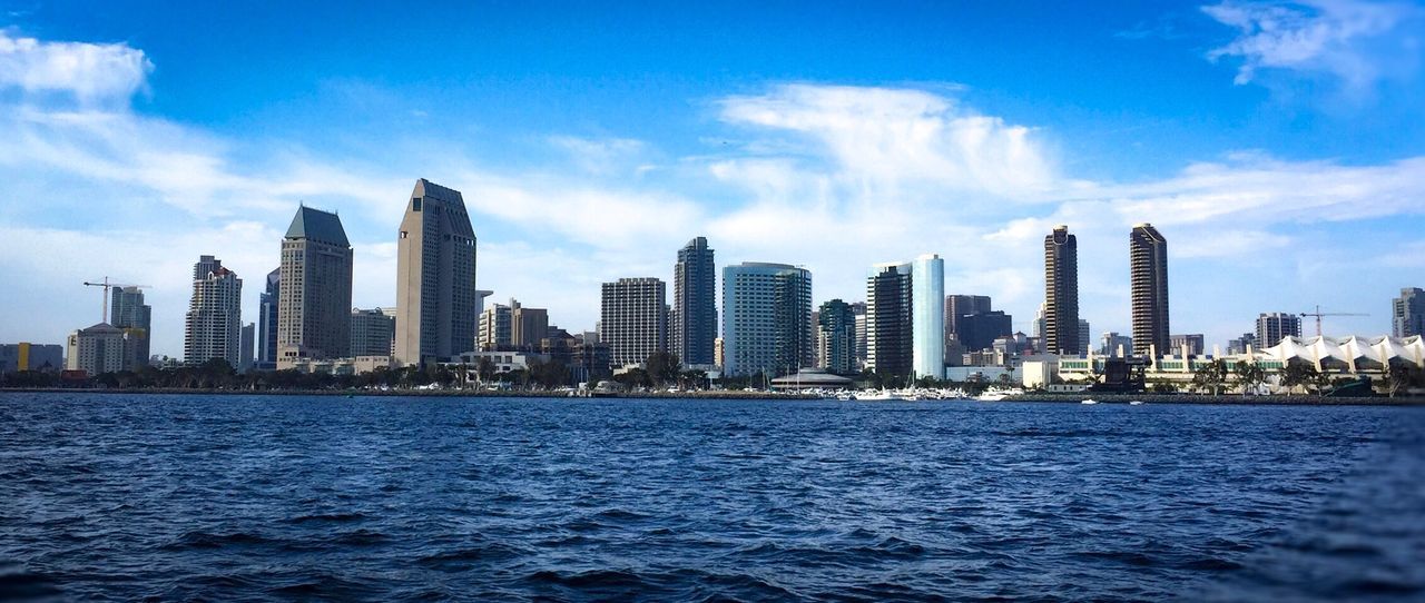 Sea by city skyline against sky