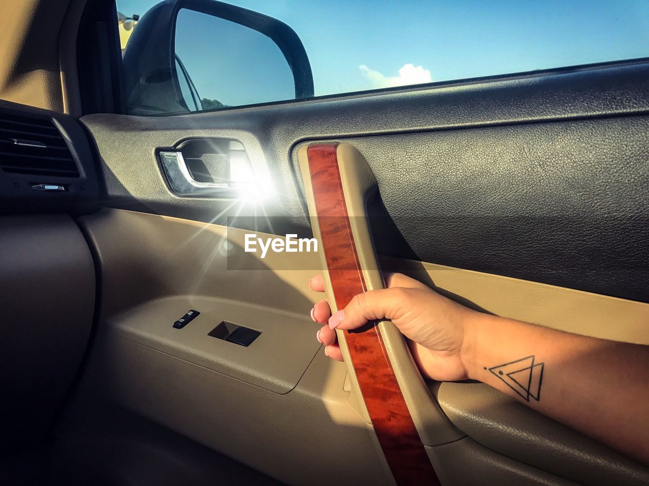 Close-up of hand holding car door against sky