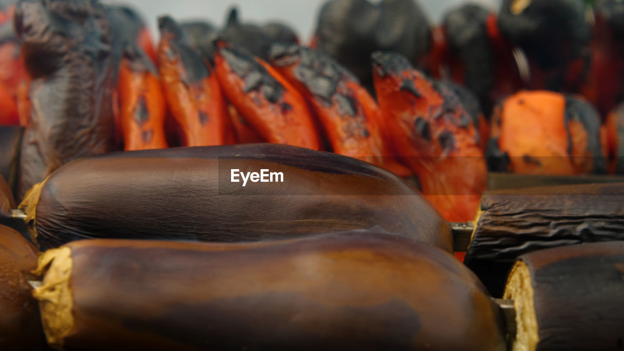 Close-up of eggplants roasted over charcoal in a charcoal grill. red peppers and tomatoes