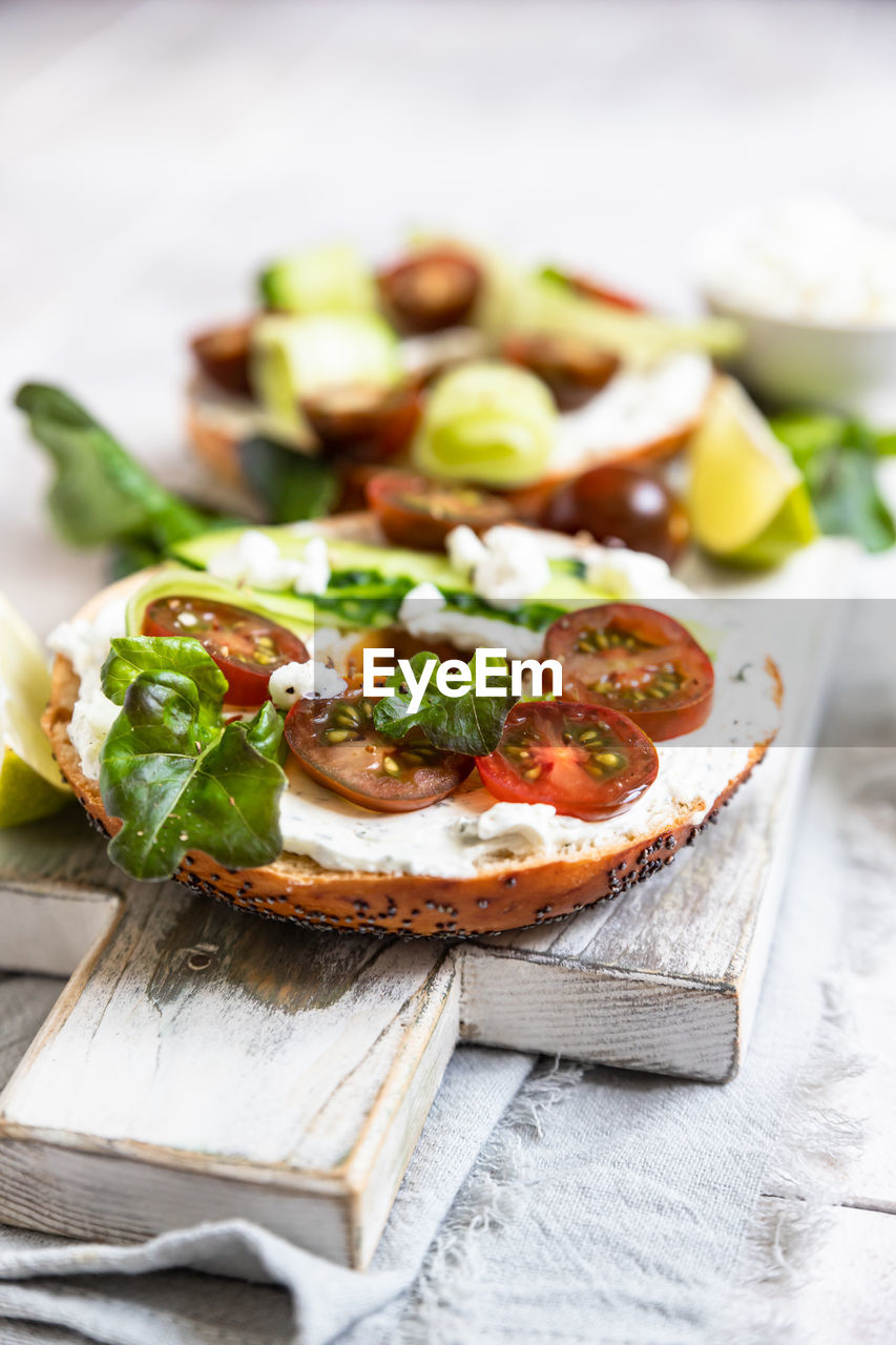 Bagels sandwich with cream cheese, cottage cheese, avocado, tomatoes, cucumbers and salad leaves