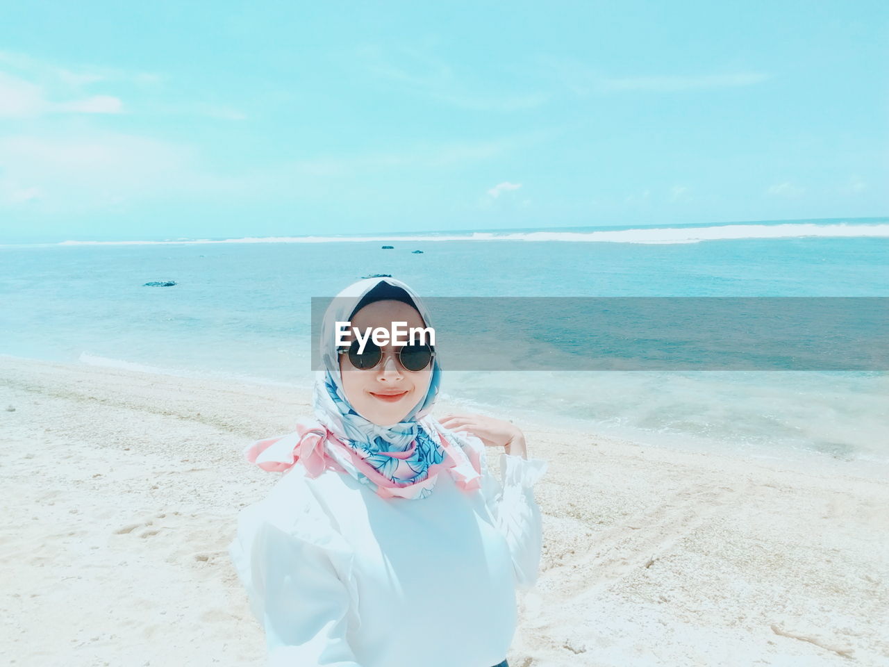 Portrait of young woman wearing sunglasses standing at beach