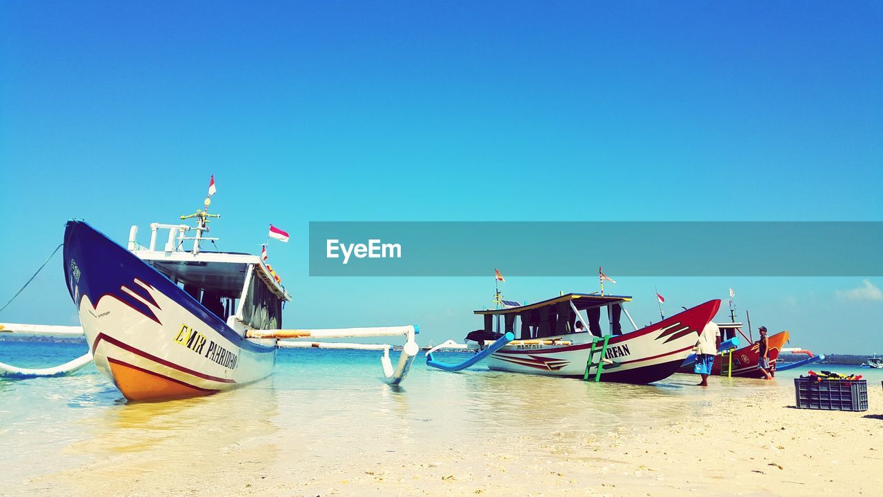 BOAT MOORED ON SEA AGAINST CLEAR BLUE SKY