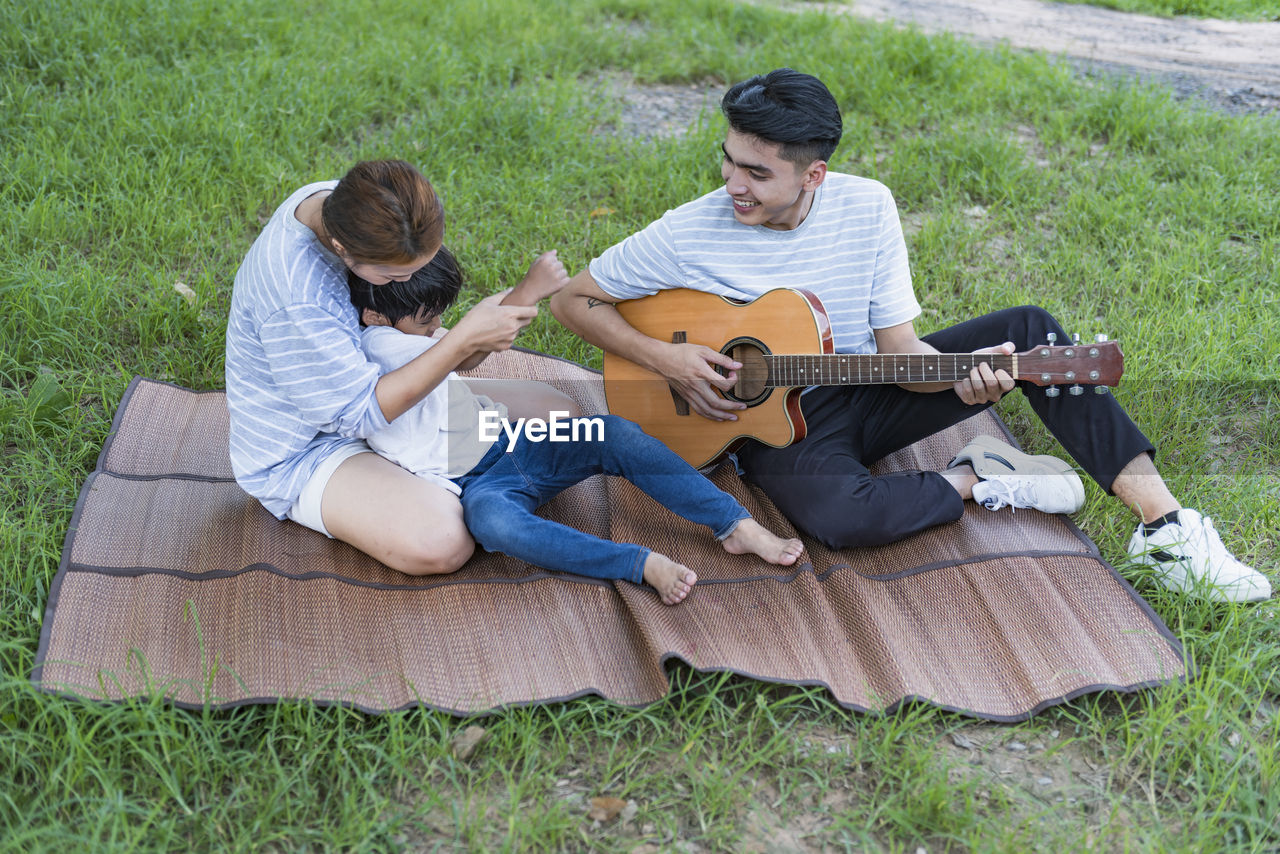 side view of young woman using laptop while sitting on field