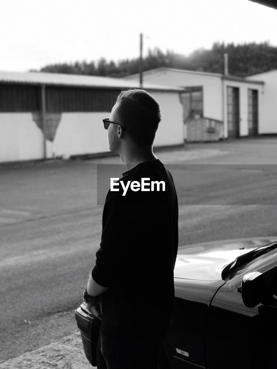 Young man standing by parked car on street