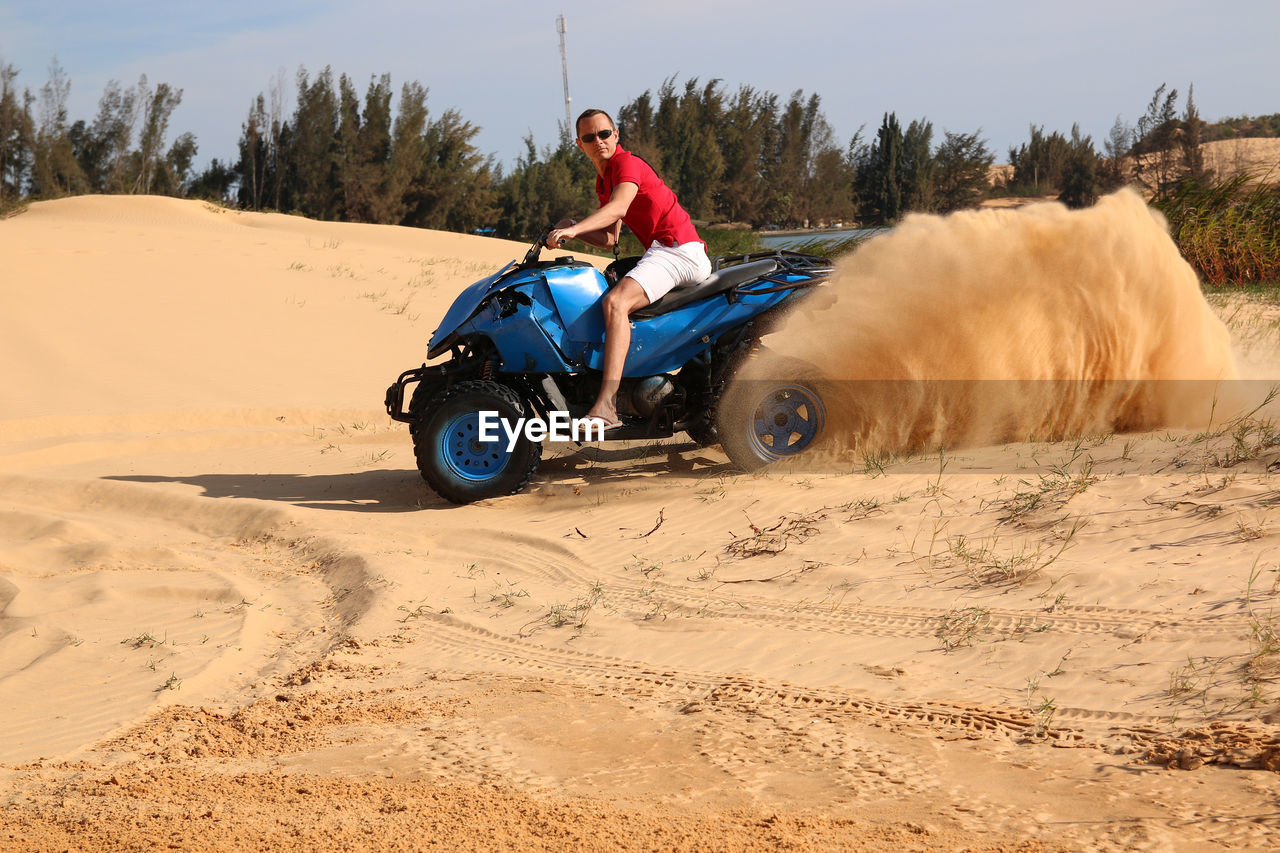 Portrait of man driving quadbike on sand