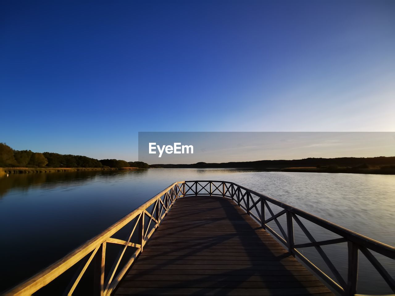 PIER OVER RIVER AGAINST CLEAR BLUE SKY